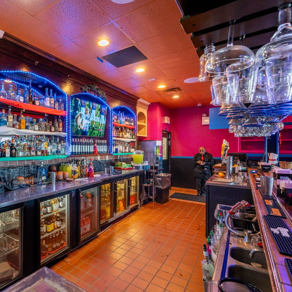 A vibrant bar at Don Eladio's Cantina with blue neon lights, liquor bottles, and a bartender.
