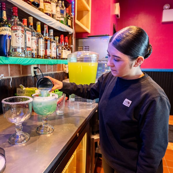 A bartender pours a green margarita into a salt-rimmed glass at Don Eladio's Cantina.