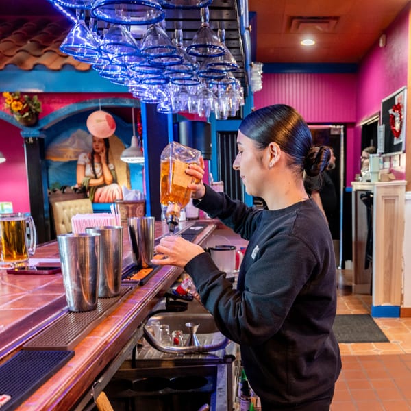 Bartender pouring liquor at Don Eladio's Cantina, with blue lit glasses hanging above the bar.