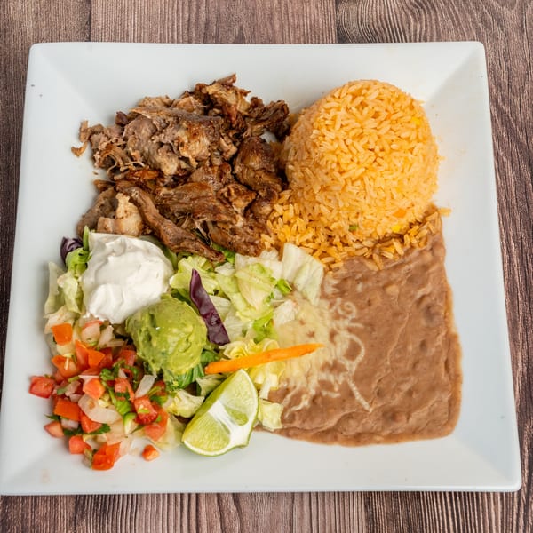 Don Eladio's Cantina's carnitas plate with rice, refried beans, salad, guacamole, sour cream, and lime.